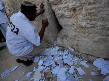 Un trabajador israelí retira los mensajes introducidos en las grietas Muro de las Lamentaciones.