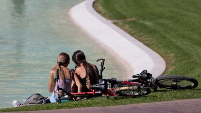Dos jóvenes descansan junto a un estanque en Valencia, este martes.