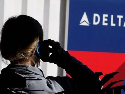Un passatger parla per telèfon davant un cartell de Delta Airlines, en una imatge d'arxiu.