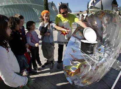 Greenpeace enseña a varios escolares cómo funciona una cocina solar.