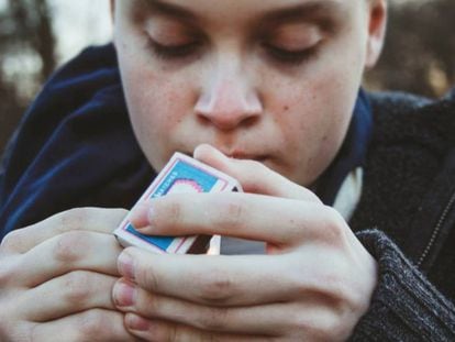Un adolescente enciende un cigarrillo.