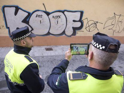 Agentes de la policía local de Málaga realizan fotos a uno de los grafitis aparecidos en una de las calles de la ciudad.