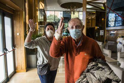 Tras recibir el alta, Francisco Javier Jiménez, de 86 años, se despide de los sanitarios en el 'lobby' del hotel medicalizado de La Paz, junto a su hija Aurora, que ha venido a buscarlo.