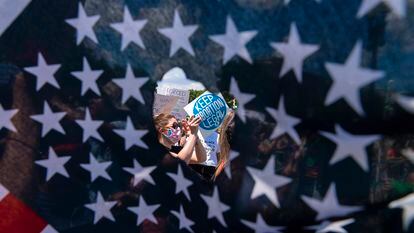 A través de un agujero en una bandera estadounidense, se observa a activistas que sostienen un letrero que lee "Mantengan legal el aborto", el 25 de junio de 2022, en Washington D. C. (EE.UU.).