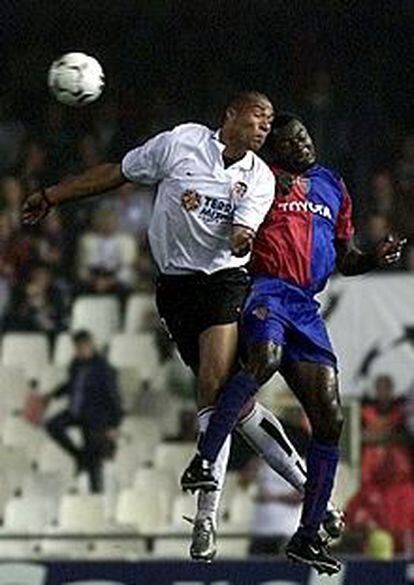 El valencianista Carew (izda.) salta con el jugador del Basilea Atouba.