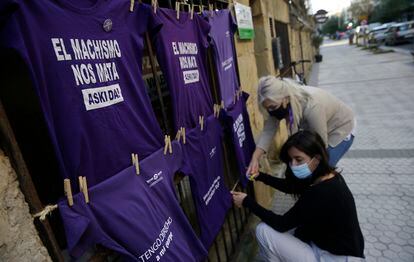 Dos mujeres colocan en una calle de San Sebastián camisetas contra la violencia machista.