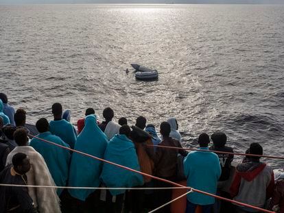Varias personas rescatadas por la ONG Open Arms en el mediterráneo central observan un bote de goma hundido en el mar de Alborán (27/12/2018).