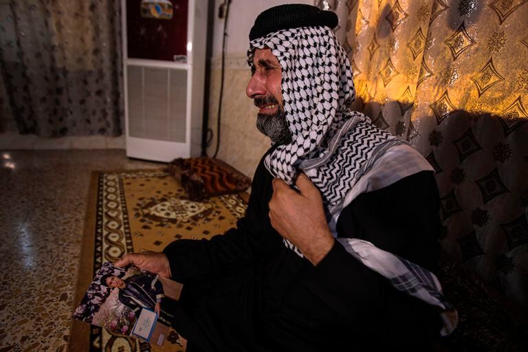Jaseb al Heliji, quien fue asesinado el miércoles pasado, llora mientras muestra una foto de su hijo en su casa en Al Amara el año pasado.