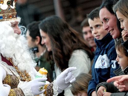 Una mujer mira sonríe al rey Melchor mientras éste saluda a los numerosos niños durante una cabalgata en Valencia.