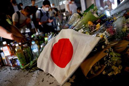 Una bandera japonesa junto a ramos de flores que ciudadanos japoneses han dejado en homenaje al ex primer ministro japonés Shinzo Abe en el sitio donde fue disparado este viernes.
