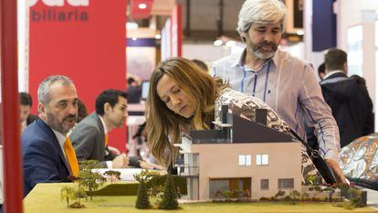 Visitantes del SIMA de Madrid miran una maqueta de una promoción de viviendas.