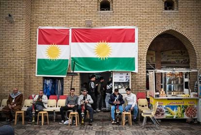 Jóvenes fuman shisha bajo dos banderas del Kurdistán iraquí en Erbil, capital de la región del mismo nombre y que goza de amplia autonomía respecto al Gobierno federal iraquí.