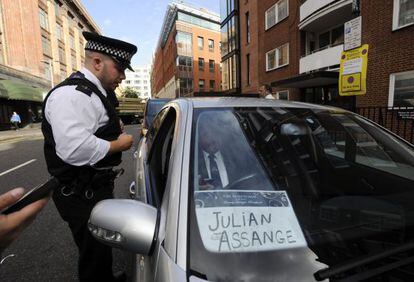 Un policía pide a un chófer que aparentemente iba a recoger a Assange frente a la embajada de Ecuador que abandone la zona.