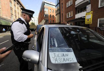 Un polic&iacute;a pide a un ch&oacute;fer que aparentemente iba a recoger a Assange frente a la embajada de Ecuador que abandone la zona.