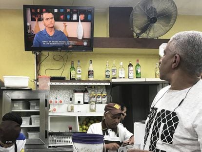 Un hombre sigue la entrevista con Jair Bolsonaro en televisión en un bar de São Paulo