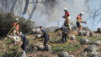 Bomberos y policía municipal de Oviedo protegen viviendas de las llamas del incendio registrado, la noche del viernes, en el Monte Naranco de Oviedo, donde tuvieron que ser desalojadas 65 personas de los núcleos de Cuyences y Fitoria. 
