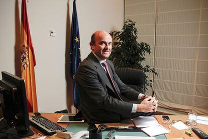 El ministro de Economía, Luis de Guindos, sentado en la mesa de su despacho del Ministerio, en Madrid.