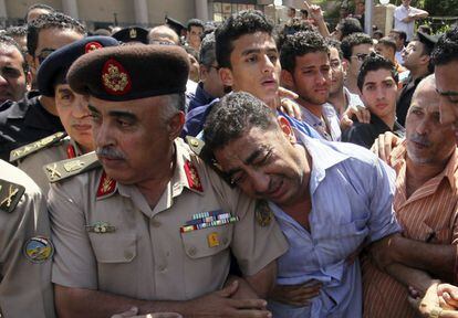 Varias personas lloran la muerte de sus seres queridos durante el funeral de los policías egipcios que fallecieron en los enfrentamientos entre manifestantes y policías en El Cairo.