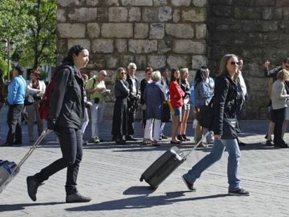 Dos mujeres pasan con sus maletas junto al Alc&aacute;zar de Sevilla.