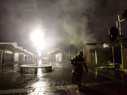 Un bombero abandona una zona comercial de la ciudad de Evreux, al oeste de Francia, aún humeante tras haber sido incendiada.
