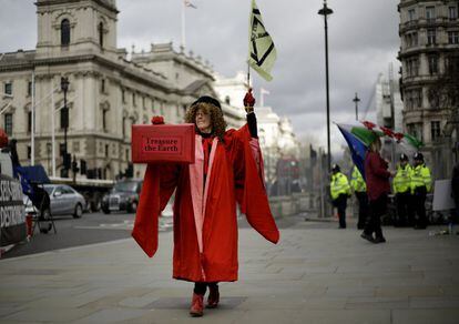 Una mujer vestida como la presidenta de la Cámara de los Comunes sujeta un estuche con el mensaje "atesora la tierra" frente al Parlamento británico. El Ministro de Hacienda británico, Rishi Sunak, anunciará el primer presupuesto desde que Gran Bretaña dejó la Unión Europea.