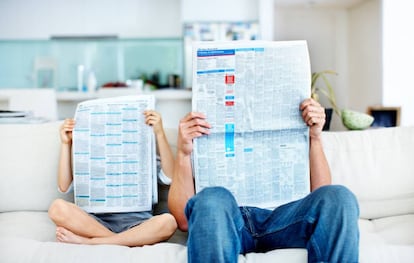 Niño pequeño y su padre leen el periódico con los rostros cubiertos