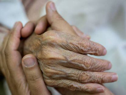 Una persona da la mano a un anciano. 