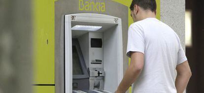 Un hombre saca dinero de un cajero automático de Bankia. EFE/Archivo