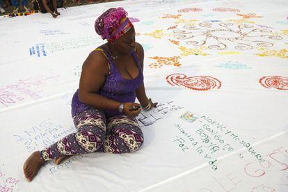 Una mujer afrocolombiana del Chocó escribe sus anhelos y deseos de construcción de paz en un gran mandala en tela realizado por las mujeres de la Ruta durante un acto simbólico que se realizó en Pereira, a mitad de camino de Popayán.