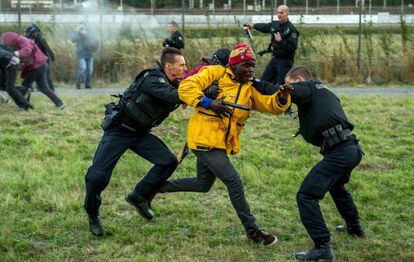 Uns gendarmes francesos detenen un immigrant a prop de l'Eurotúnel, aquest dijous a Calais.