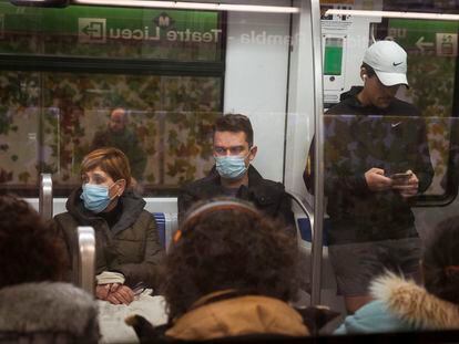 Varios usuarios del metro de Barcelona con mascarillas.
