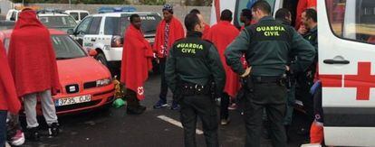 Agentes de la Guardia Civil y de Cruz Roja atienden a un grupo de inmigrantes que ha desembarcado este sábado en Ceuta.