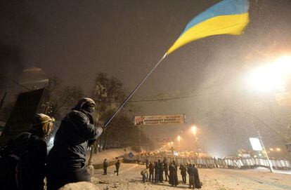 Un activista ondea una bandera ucraniana desde un abarricada en el centro de Kiev.