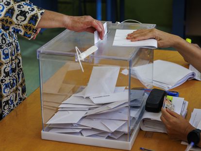 Una mujer introduce su voto en una urna en un colegio electoral de Sevilla.