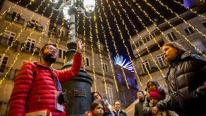 El guía José Manuel Pájaro acompaña a un grupo de turistas en el centro histórico de Vigo en un 'freetour' por las luces navideñas.