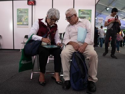 Dos personas comparan estrategias en la Feria de las Afores 2023 en Ciudad de México.