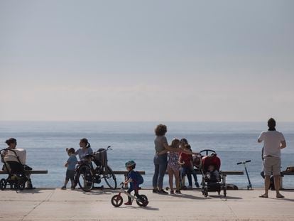 Familias pasean por el paseo marítimo de Barcelona.