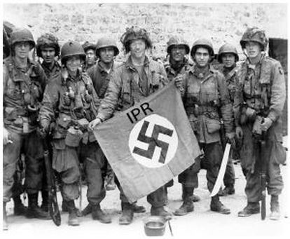 Soldados estadounidenses exhiben una bandera nazi capturada.