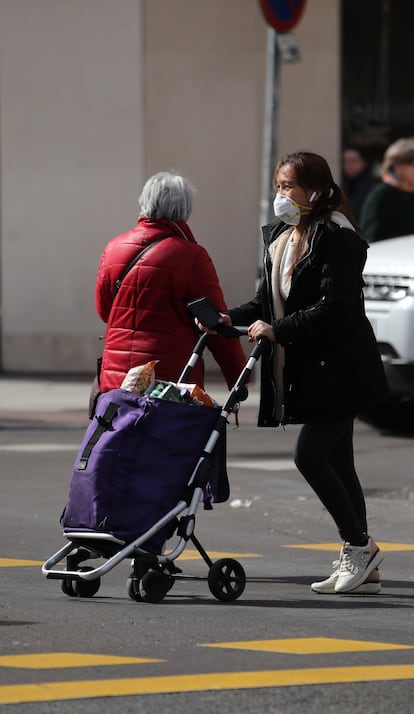 Una mujer con mascarilla empuja su carro de la compra por el centro de la capital.