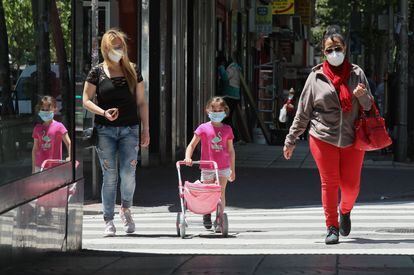 Adultos y niños pasean con mascarillas en Madrid.