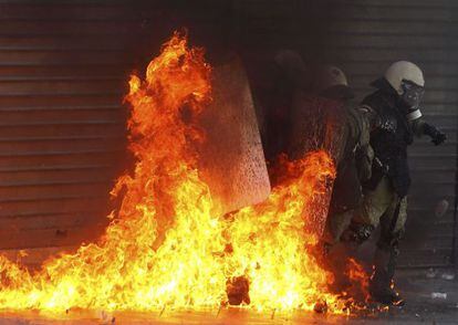 Policías antidisturbios se ven envueltos por las llamas de una bomba molótov durante los choques violentos de hoy, en Atenas.