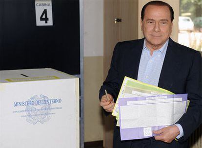 El primer ministro italiano, Silvio Berlusconi, se prepara para introducir su voto en la urna en Milán.