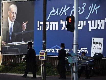 Dos ultraortodoxos caminan cerca de un cartel electoral de Netanyahu en Ramat Gan, cerca de Tel Aviv.