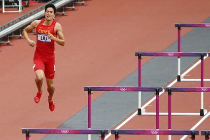 El chino Liu Xiang, con una lesión en el pie, se aproxima tras la carrera a la valla donde se produjo su caída.