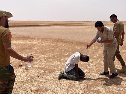 Un agente de fronteras libio le echa agua a un migrante africano en la frontera entre Libia y Túnez, este 30 de julio.