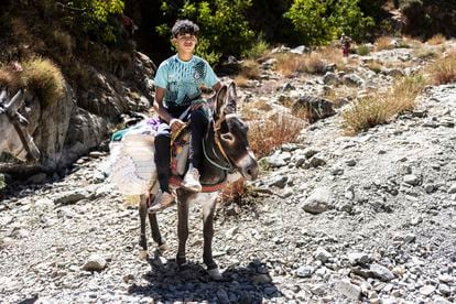 Abdeltif, de 18 años, vecino de Amndar, posa a lomos de un burro con la ayuda humanitaria que lleva a su pueblo.