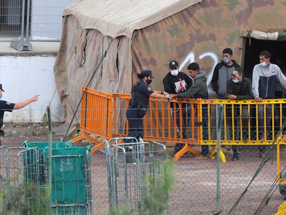 Varios inmigrantes hablaban ayer con agentes de la Policía Nacional en el campamento de atención temporal del antiguo polvorín de Barranco Seco.