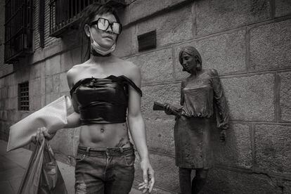 Una mujer camina junto a la estatua llamada 'Tras Julia', en el barrio de Malasaña, levantada por Antonio Santín en honor a las primeras españolas que fueron a la universidad.