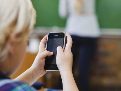 Un niño usa el móvil durante una clase.