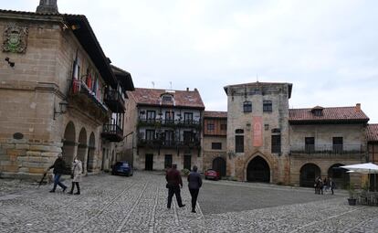 Visitantes pasean por la plaza Mayor de Santillana del Mar, con el Ayuntamiento a la izquierda y la Torre de Don Borja al frente.